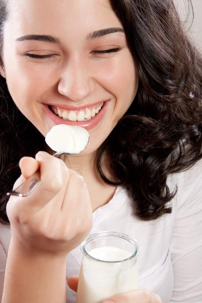 A woman enjoying a bowl of yogurt, savoring each spoonful with delight.